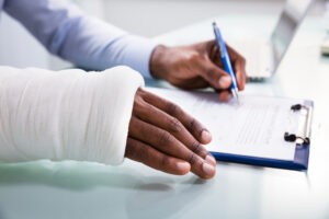 Why You Need A Lawyer For Workers' Compensation - Injured Man Filling Insurance Claim Form